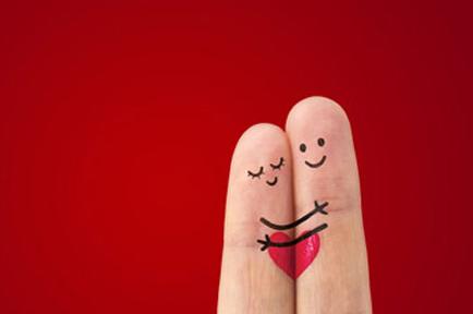 Two fingers with features drawn on hugging